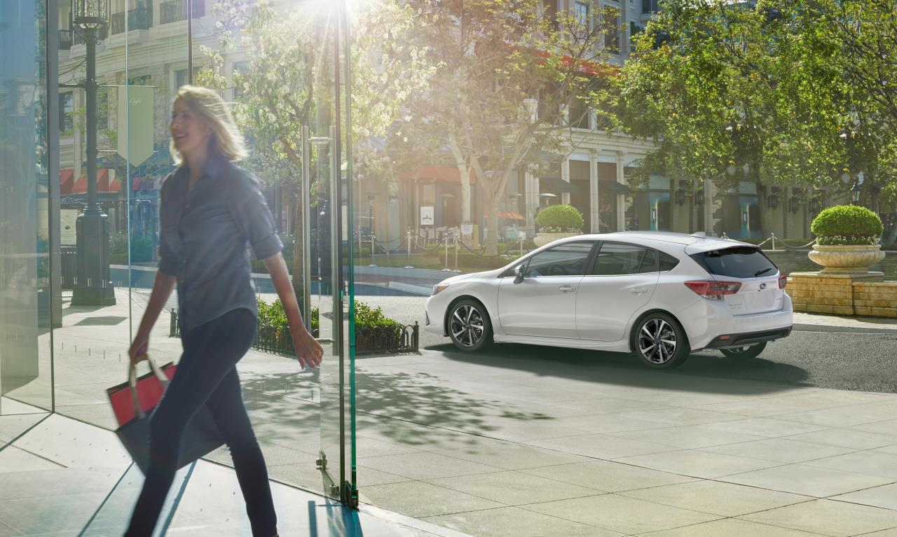 un femme rentrant dans un immeuble et la Subaru Impreza 2020 stationné à l'extérieur